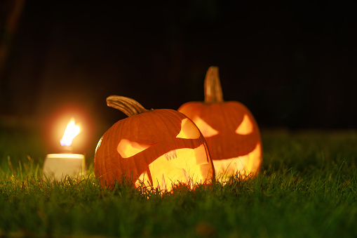 Jack O'Lanterns - Carved Pumpkins - Scary Halloween Decorations - Lanterns - Candles \nIn the Grass