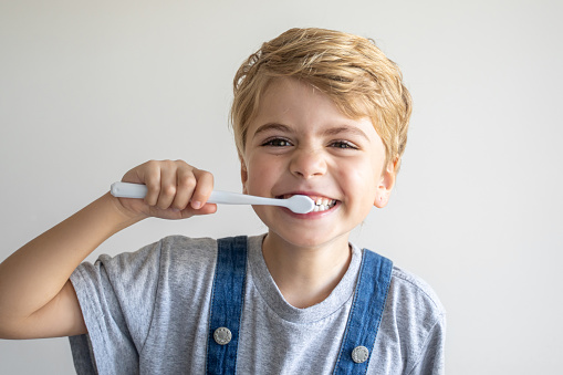 Cute child brush teeth toothbrush, smiling over white background. Studio shot. Dental hygiene, morning routine, lifestyle, tooth care, children health.