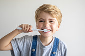 Cute child brush teeth toothbrush, smiling over white background. Studio shot. Dental hygiene, morning routine, lifestyle, tooth care, children health.