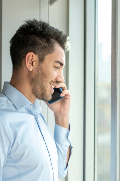 istock Young adult man talking on the phone by the window 1437745776