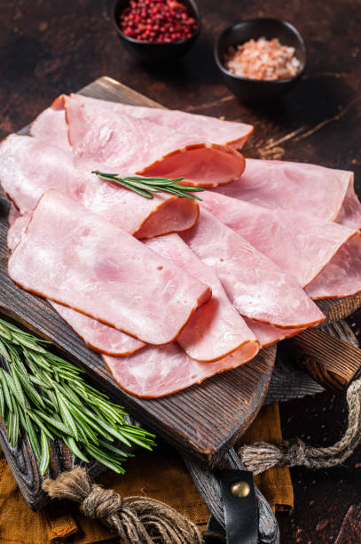 istock Flat slices of square sandwich ham with herbs. Dark background. Top view 1437746458