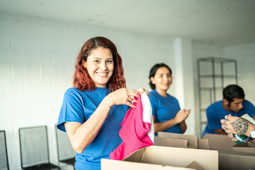 Portrait of mid adult volunteer woman folding a clothing