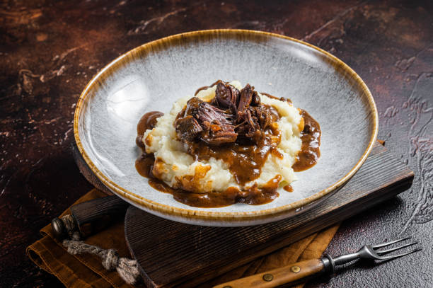 istock Slow cooked beef cheeks in red wine sauce with mashed potato. Dark background. Top view 1437747746