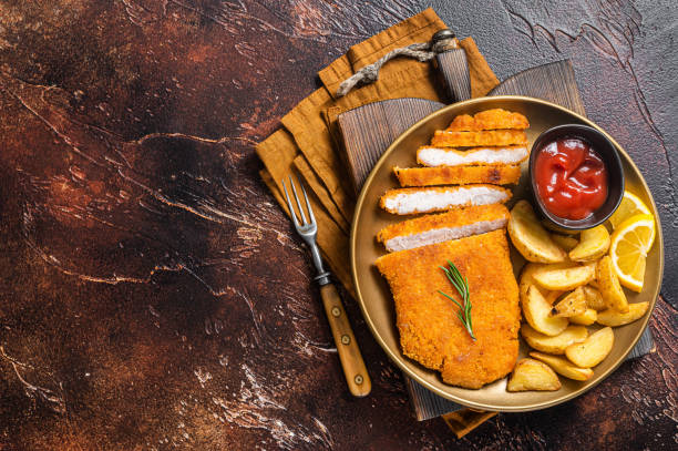 breaded german weiner schnitzel with potato wedges. dark background. top view. copy space - weiner schnitzel imagens e fotografias de stock