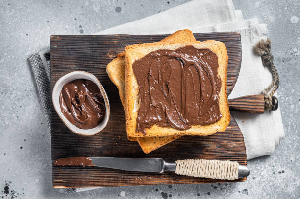 istock Toast with chocolate Hazelnut spread on wooden board. Gray background. Top view 1437751119