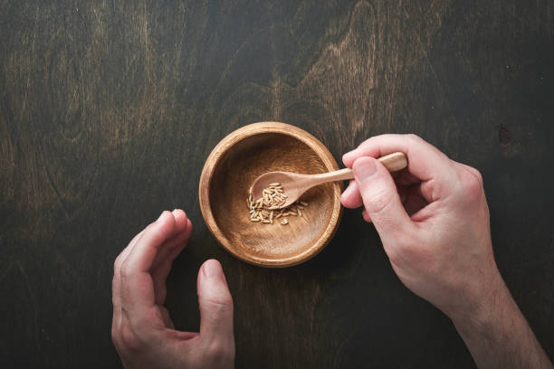 World food crisis concept. Male hands take very small portion of grain food from bowl on gloomy background as symbol of global food crisis. Hunger due to lack of grain. Food supply crisis. Top view. concepto de crisis alimentaria mundial. las manos masculinas toman una porción muy pequeña de alimentos de grano de un tazón sobre un fondo sombrío como símbolo de la crisis alimentaria mundial. hambre por falta de grano. crisis del suministro de alim