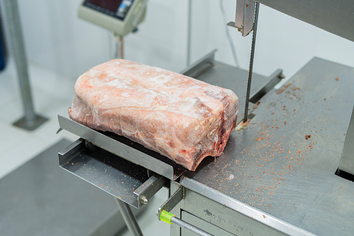 Butcher uses the bone slicer to slice pieces of meat and make it ready