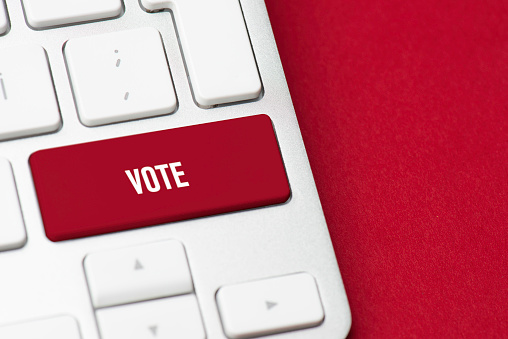 Modern keyboard with red vote button on red paper.