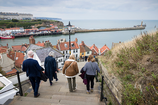 Whitby, UK - September 21, 2022. Tourists walk down Whitby Abbey steps toward Whitby Harbour. Whitby, Yorkshire, UK