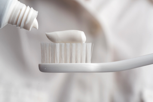 Close-up of toothbrush and a tube of toothpaste in a woman's hands