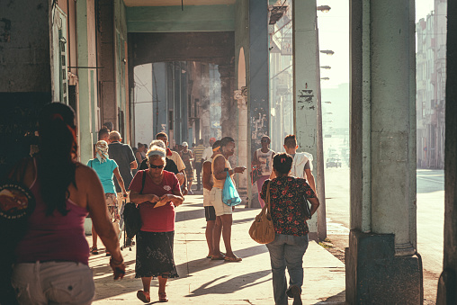 Havana, Cuba - March 19, 2015: Local people walk in the sunny morning on walkway with arches in central Havana, Cuba.