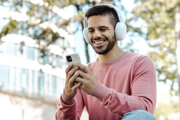 istock Smiling man looking at his phone with headphones on 1437758917