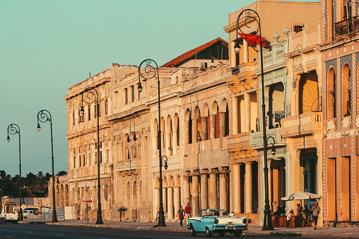 Havana, Cuba - March 19, 2015: Street scene with old American car and worn out buildings in Havana, Cuba. Tourists and local people walking along the street at Malecon.