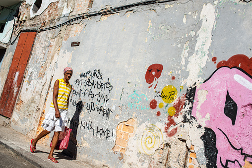 Havana, Cuba - March 18, 2015: Cuban woman passing a wall with colorful graffiti.