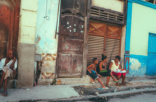 Havana, Cuba - March 18 2015: Cuban People relaxing and sitting in the street on a sunny day in Havana, Cuba.