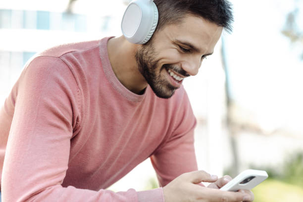 istock A young man is sitting and using his phone with a headphones on 1437759250