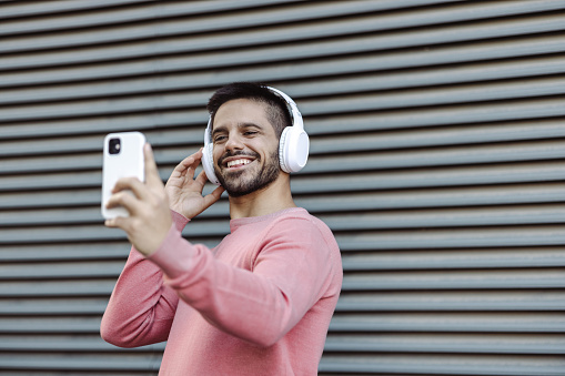 A young man posing to take a selfie with his headphones on