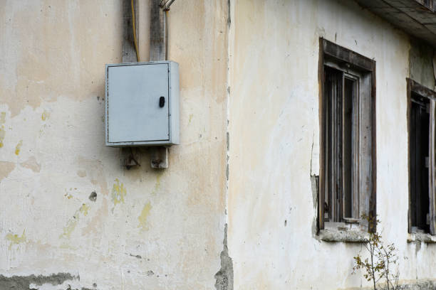 Old house electric panel, electric panel hanging on the old and abandoned building exterior