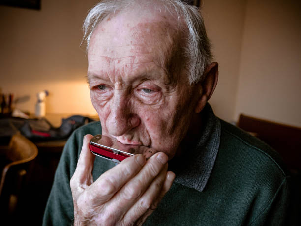 Portrait of an old man playing harmonica, senior, indoor, face, music, musical instrument, hobby.