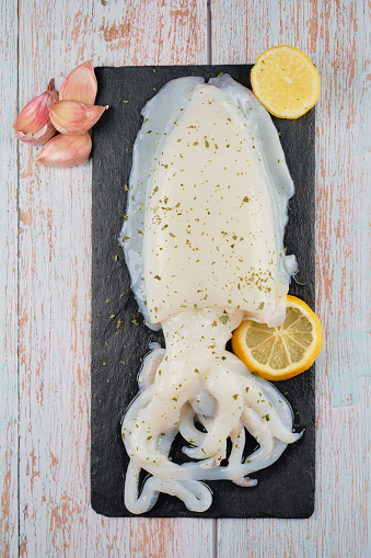 Cuttlefish sepia on dark stone plate with lemon and garlic copy space wood background fresh and healthy sea food