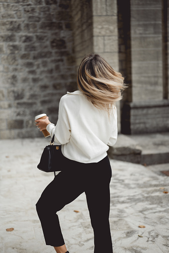 rear view of a woman in motion with blond hair. tossing hair while walking in city street