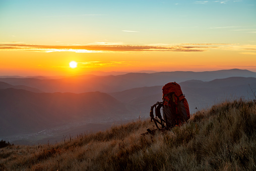 Hiking backpack in the mountains against wonderful sunset