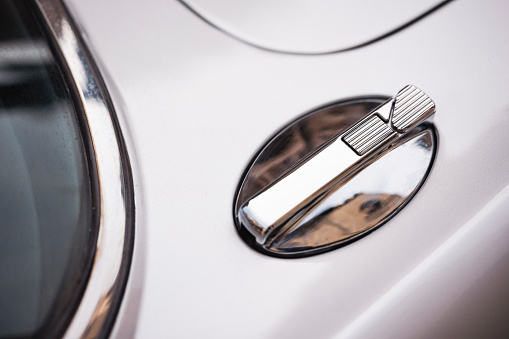 Fuel tank cap with key slot on white vintage car or bus.