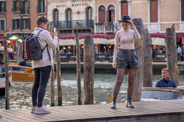 Venice, Italy - October 10th 2022: Beautiful young woman posing for a photograph in front of the Rialto Bridge in the center of the old and famous Italian city Venice