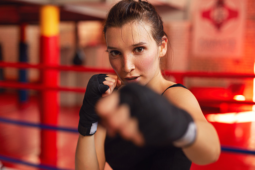 Portrait of a sporty young woman working out with a punching bag