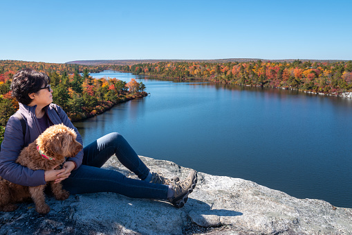 Senior woman enjoying Autumn weather and the view of fall foliage with her dog