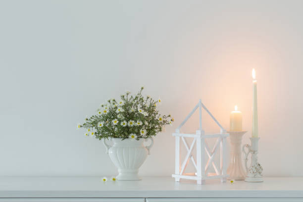 istock white flowers in white ceramic vase with burning candles in white interior 1437782059