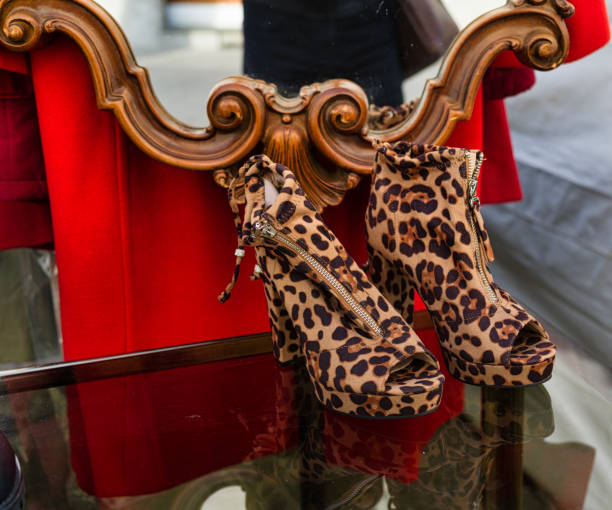 One pair of female tiger print platform sandals with heels lies in the center on a pink flat lay background. The concept of fashion, beauty, shoes.