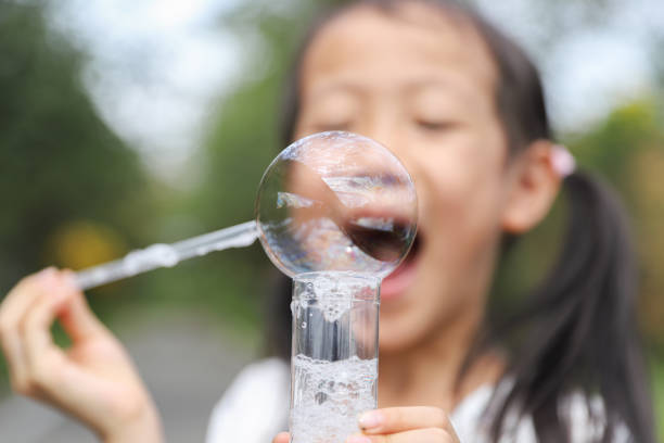 a Asian girl is blowing bubbles in the park.