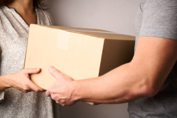 istock Delivery man giving cardboard box to female hand 1437790065