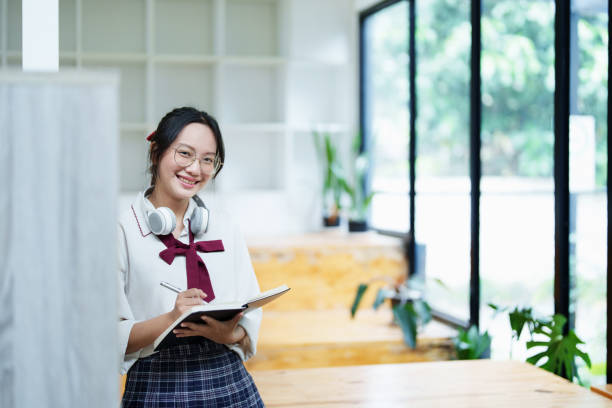 istock Portrait of a beautiful young Asian student using a notebook to take notes in the library 1437792495