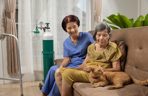 Elderly woman wearing oxygen nasal cannula at home.