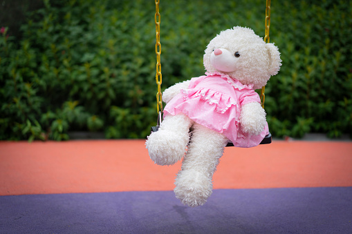 The teddy bear swings in the playground