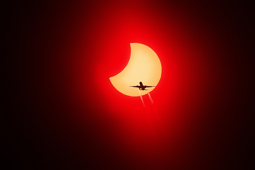 Airplane passing in front of the sun during a solar eclipse.