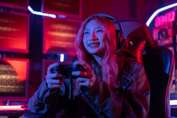 istock You win. Gamer using joystick controller plays online video game with computer neon lights backgrounds, woman use gaming headphones playing live stream esports games console at home. 1437805389