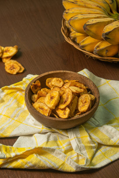 istock Crispy and delicious banana chips on a wooden background 1437806263