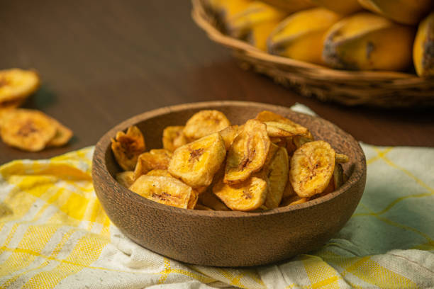 istock Crispy and delicious banana chips on a wooden background 1437806276