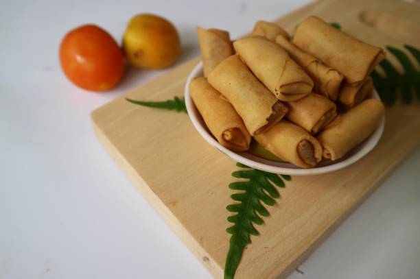 istock Sumpia or mini crunchy spring rolls on white plate and wooden cutting board. Indonesian homemade crispy fried snack, Wrapped by Kulit Lumpia and filled with Ebi or Shredded Shrimp. 1437807421