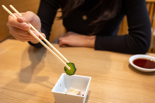 Asian woman picking up cucumber 'Tsukemono' pickles using chopstick