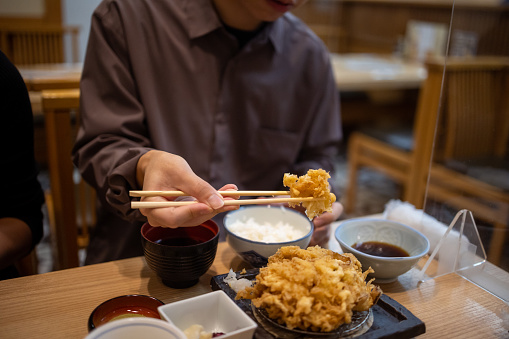 Young Asian man visting Japan and eating Kakiage Teishoku in Japanese restaurant