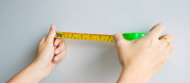 istock Man hand using tape measure for measuring with wall backgrounds at home. DIY, Interior design, repairing and improvement home or apartment concepts 1437809043