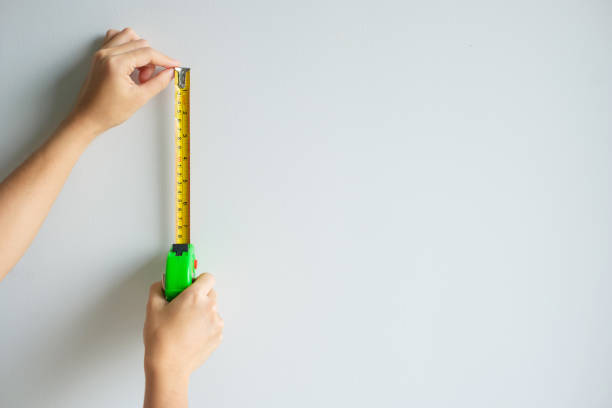 istock Man hand using tape measure for measuring with wall backgrounds at home. DIY, Interior design, repairing and improvement home or apartment concepts 1437809045