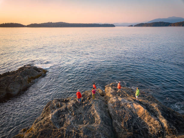 Extended Multiracial Two Generation Family Watching Sunset From Rocky Shore