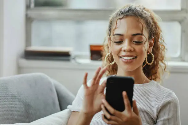 Photo of Black woman with smartphone on a sofa for networking online, mobile app or relax chat with home wifi. Young person on couch using phone for internet, social media post or email communication update