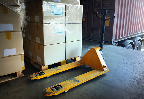 Hand Pallet Truck with Packaging Boxes Stacked on Pallets. Hand Lift, Pallet Jack Loader. Supply Chain Goods. Storehouse Distribution. Cargo Shipping Supplies Warehouse Logistics