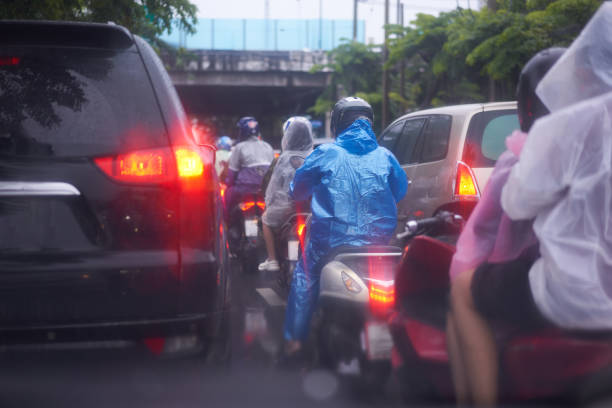 motorcycle driver on raincoat ride in traffic rain road